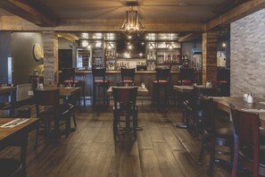 A restaurant interior with wooden floors, bar area, and seating. - Hotel Continental (Val-d'Or)