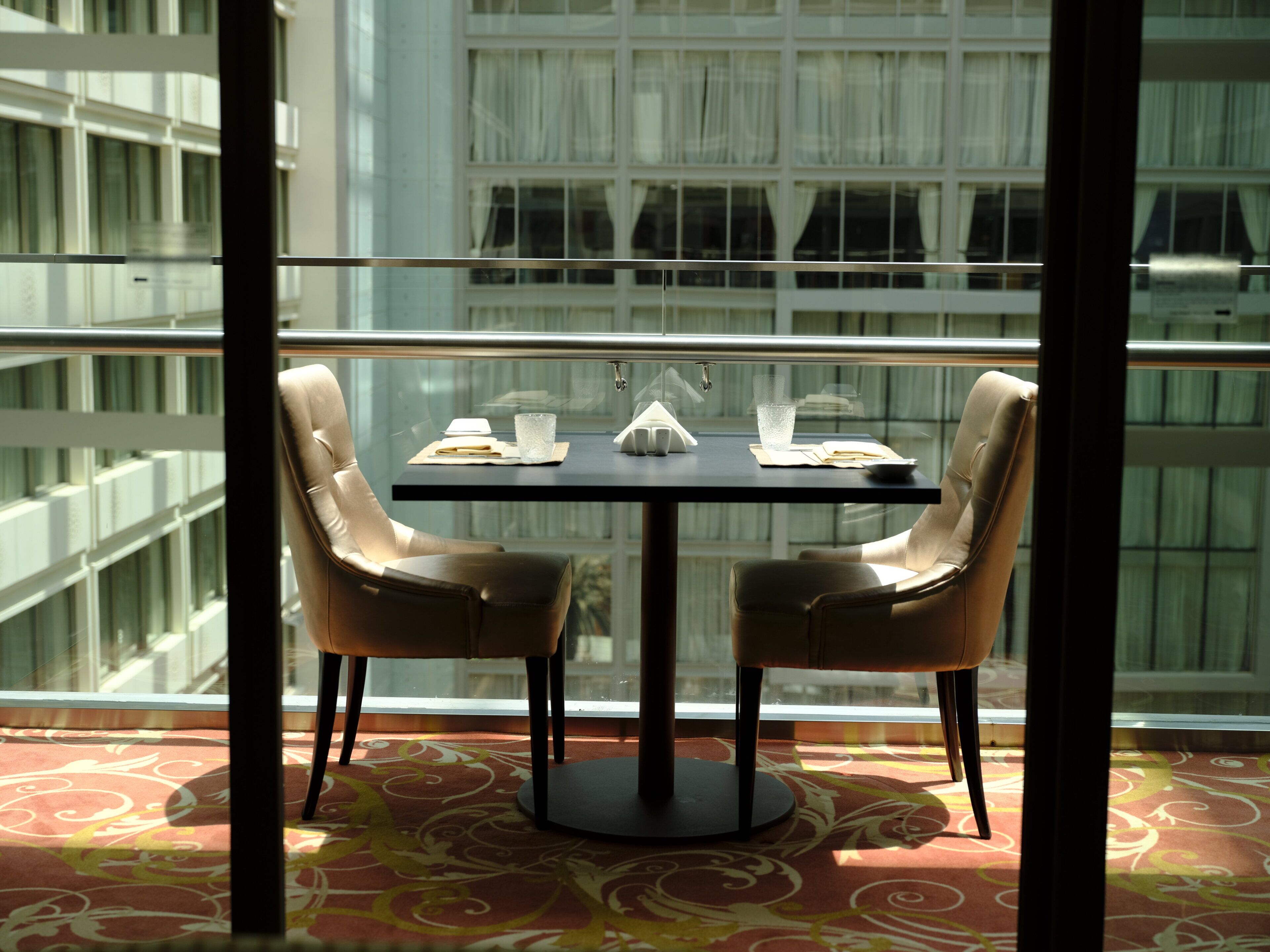 Un coin repas avec une table, deux chaises, un verre d’eau, un livre et une serviette sur la table.