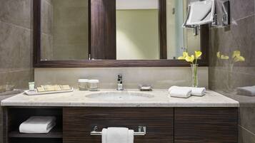 A modern bathroom with a large mirror, a sink, and a vanity with storage drawers.