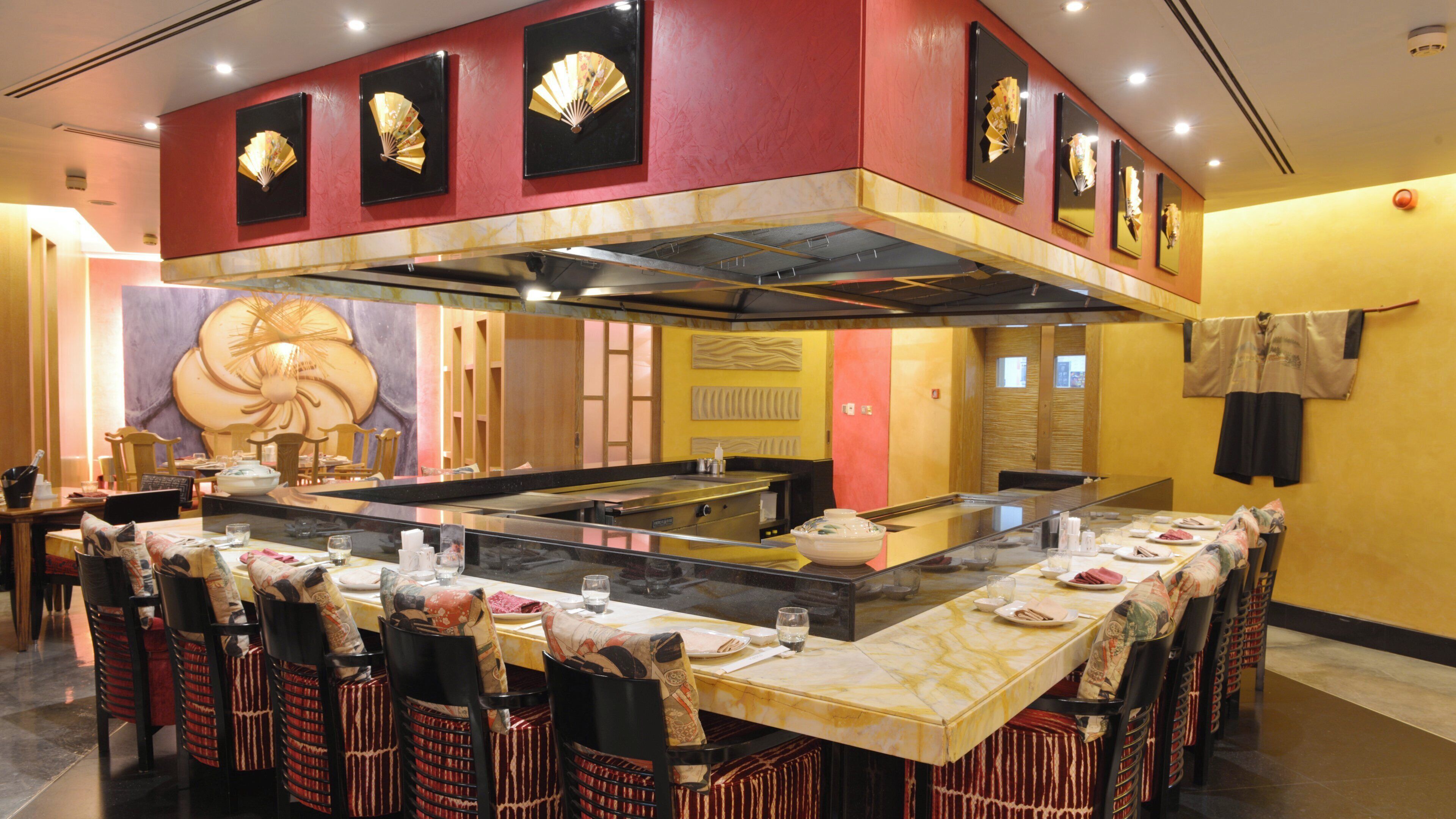 A restaurant with a central island, multiple dining tables, and chairs.