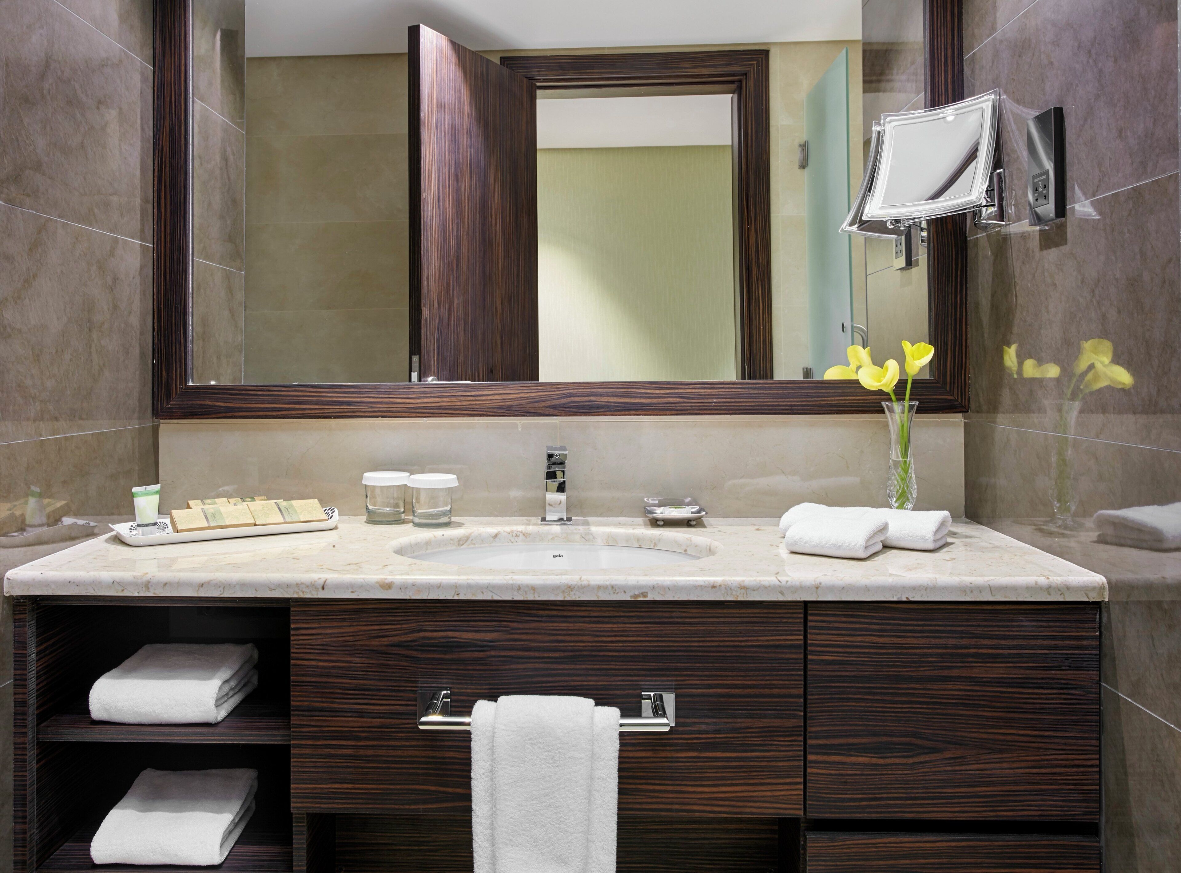 A bathroom with a large mirror, a sink, a vanity with drawers, and a towel rack.
