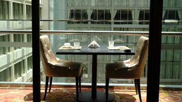 A dining area with a table set for two, a glass of water, and a menu.