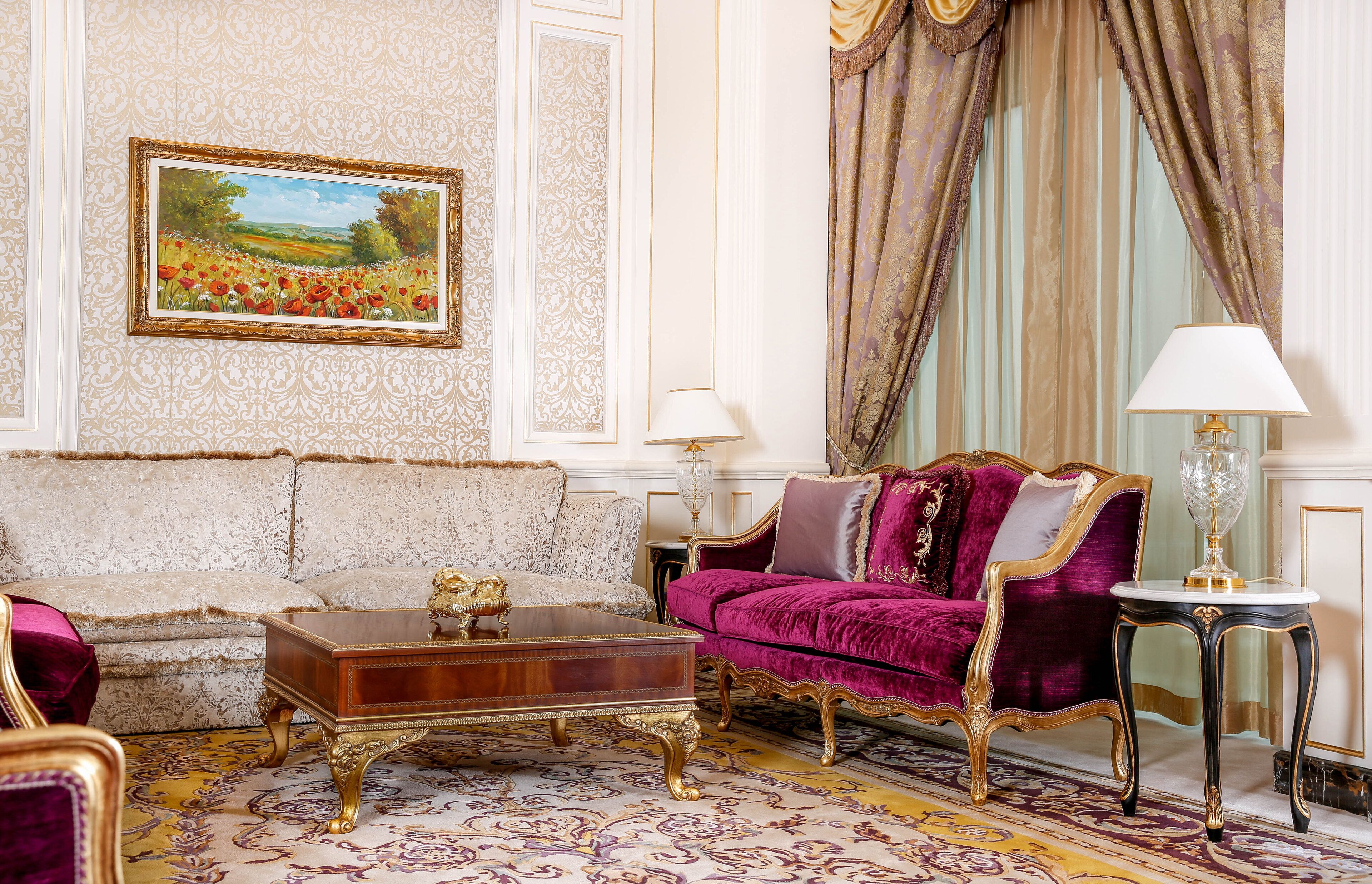 Un salón lujoso con muebles ornamentados, un cuadro grande y cortinas elegantes.