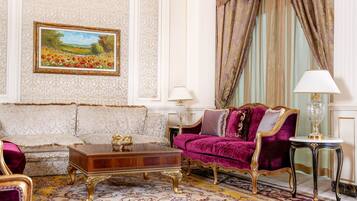 Un salón lujoso con muebles ornamentados, un cuadro grande y cortinas elegantes.