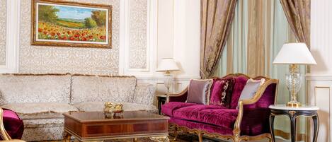 A luxurious living room with ornate furniture, a large painting, and elegant curtains.