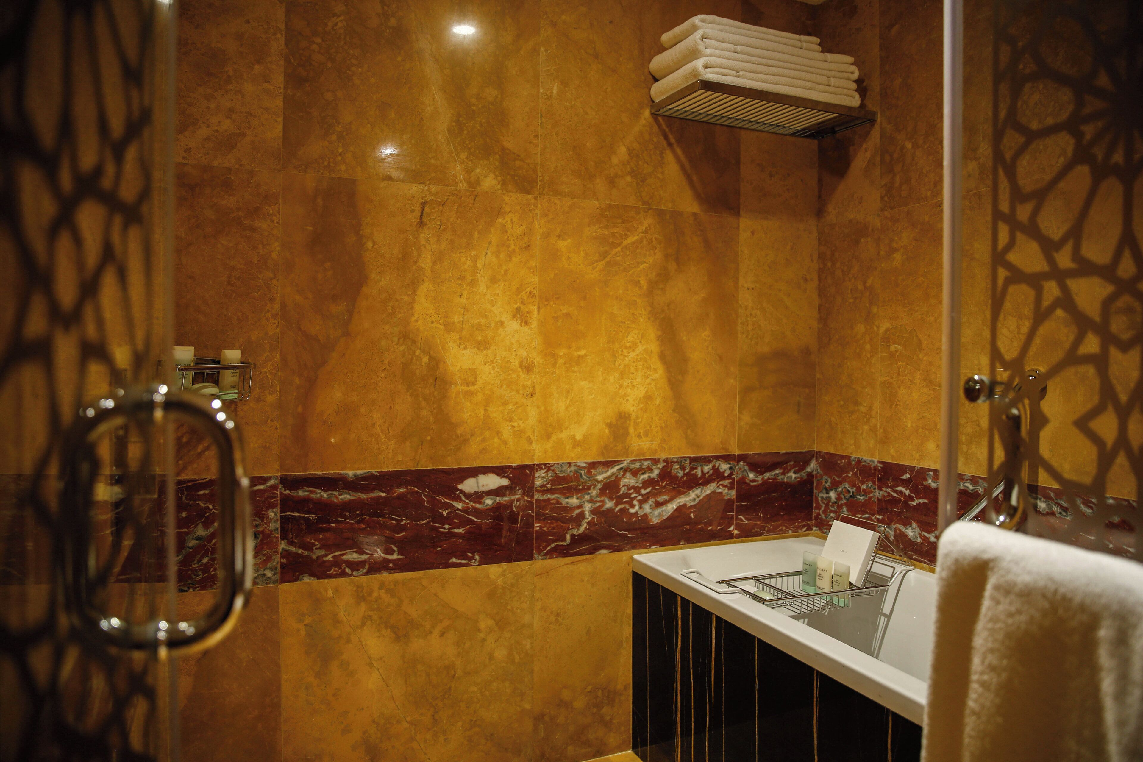 A bathroom with a marble wall, a white sink, and a towel rack.