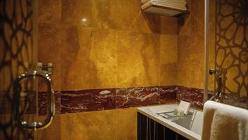 A bathroom with a marble wall, a white sink, and a towel rack.