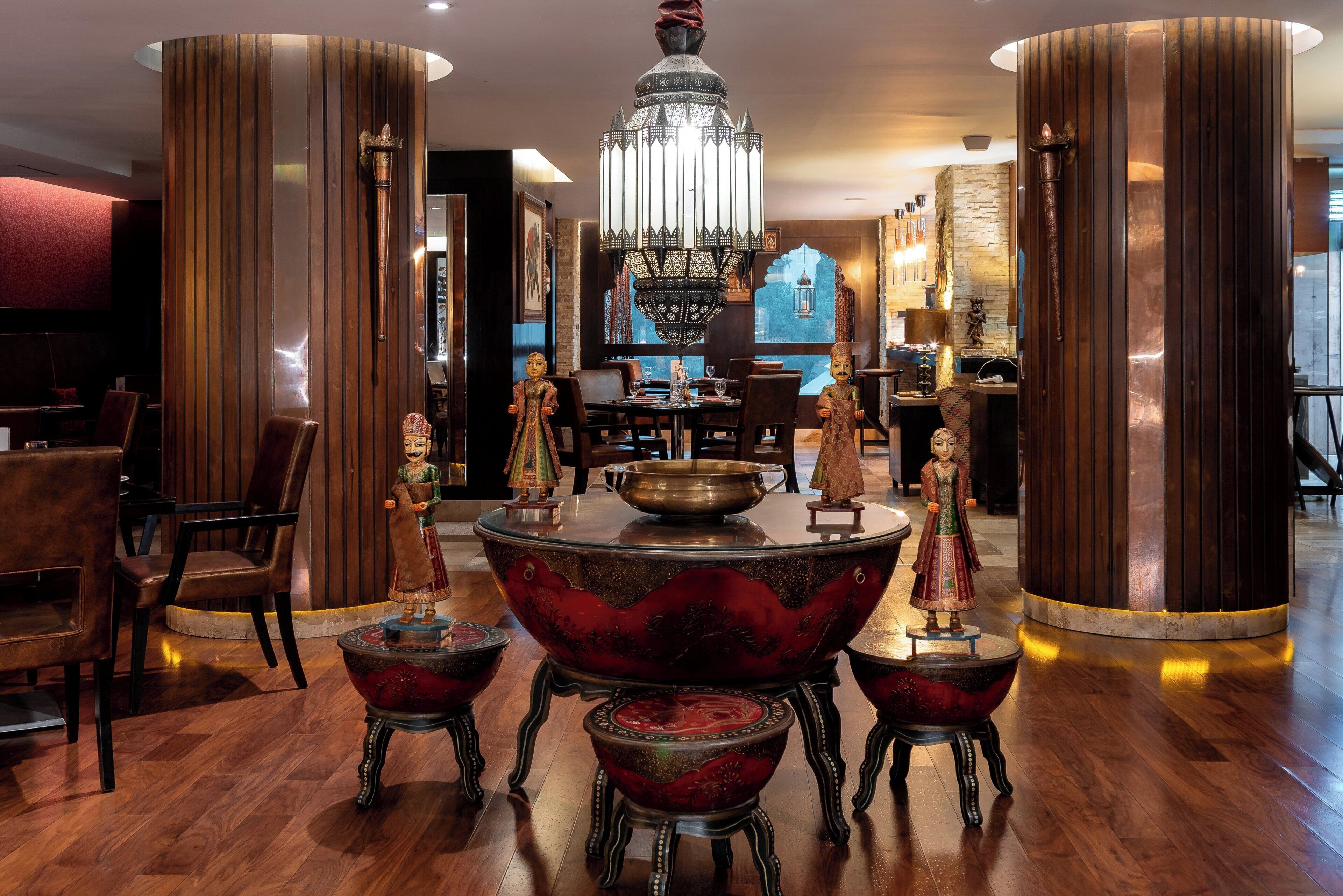 Un interior tradicional con una mesa central adornada, altos pilares de madera y una araña.