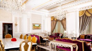 A luxurious room with a marble table, gold chairs, a purple sofa, and ornate chandeliers. - Crowne Plaza Kuwait Al Thuraya City by IHG (Farwaniya)