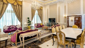 A luxurious living room with a sofa set, a dining table, and a chandelier. - Crowne Plaza Kuwait Al Thuraya City by IHG (Farwaniya)