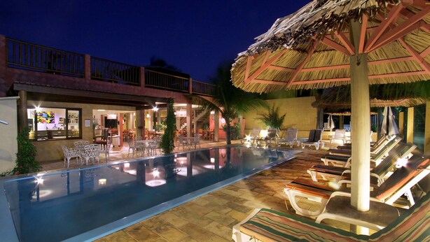 A swimming pool with lounge chairs and a bar area. - Pousada Só Alegria (São Miguel do Gostoso)
