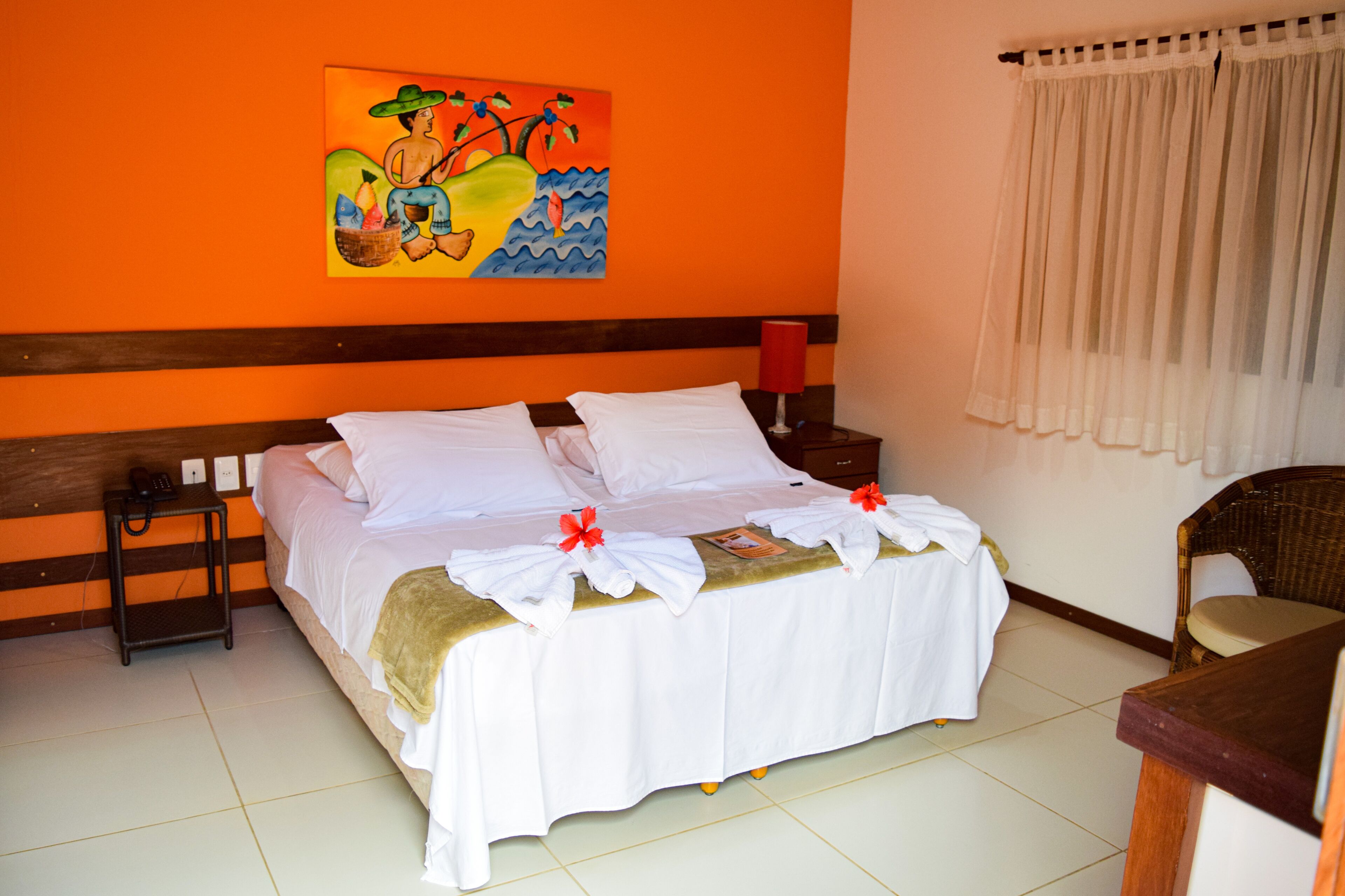 A hotel room with a large bed, a nightstand, a chair, and a painting on the wall.