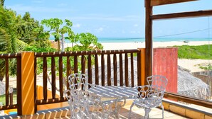 A wooden pergola with a table and chairs, overlooking a beach. - Pousada Só Alegria (São Miguel do Gostoso)