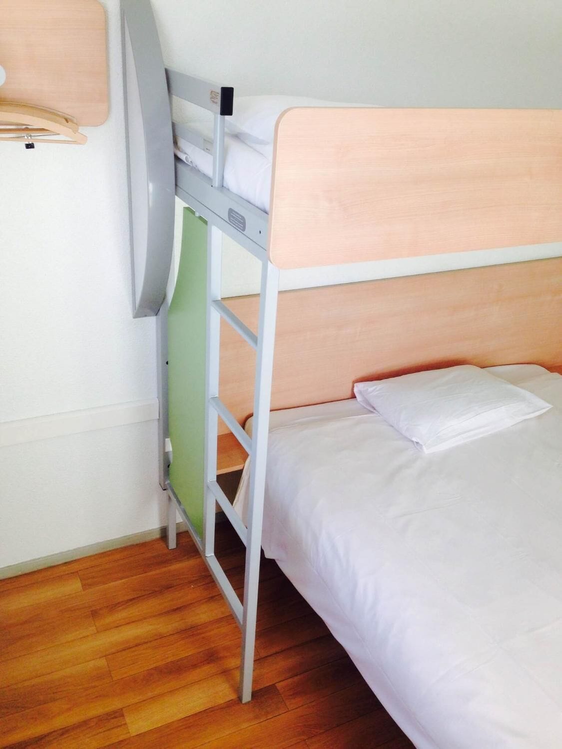 A bunk bed with a wooden headboard and white bedding.