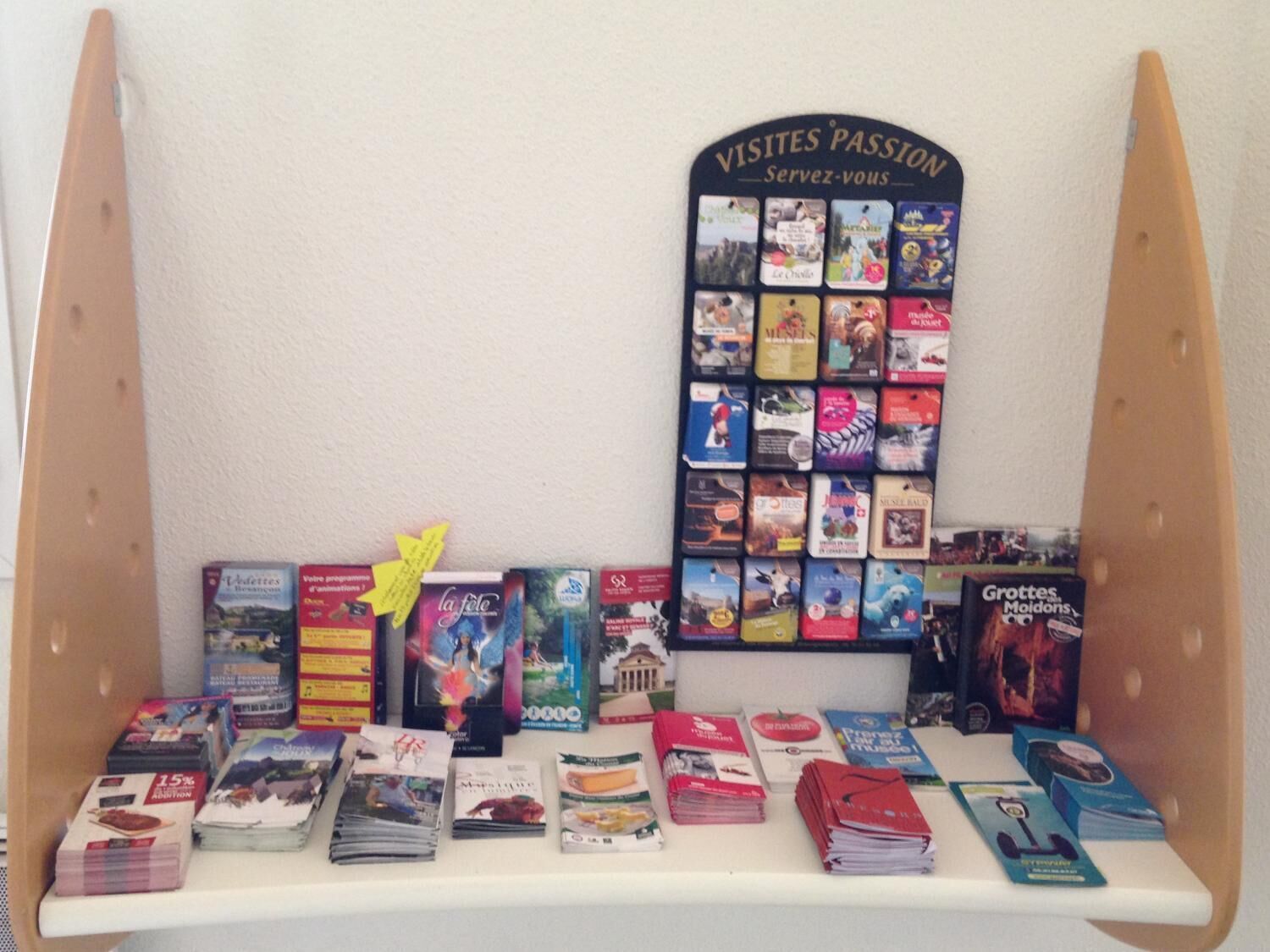 Una exhibición de libros de viaje con un letrero que dice "VISITES PASSION Servez-vous" y varias guías de viaje y folletos.