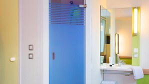 Une salle de bain avec une douche, un lavabo avec un miroir et un porte-serviettes.