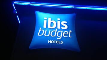 A sign for 'ibis budget hotels' with a blue neon light.