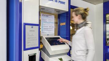 A check-in point with a digital kiosk and a sign indicating 'CHECK-IN POINT'.