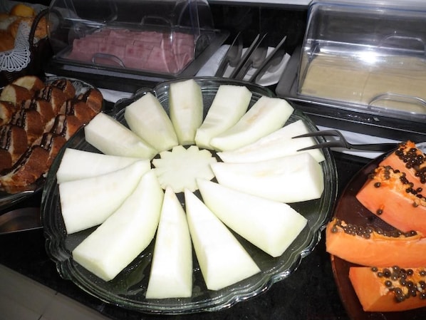 A buffet with various food items including sliced apples, bread, and a dish with a central white item surrounded by apple slices. - Perolas Do Mar Pousada (Maceio)