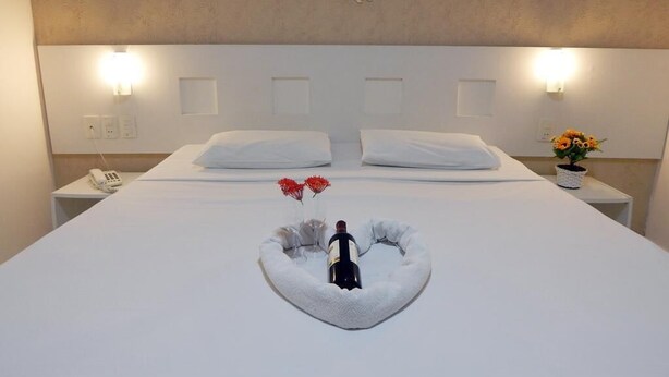 A hotel room with a large bed, white headboard, and a decorative fish wall art piece. - Perolas Do Mar Pousada (Maceio)
