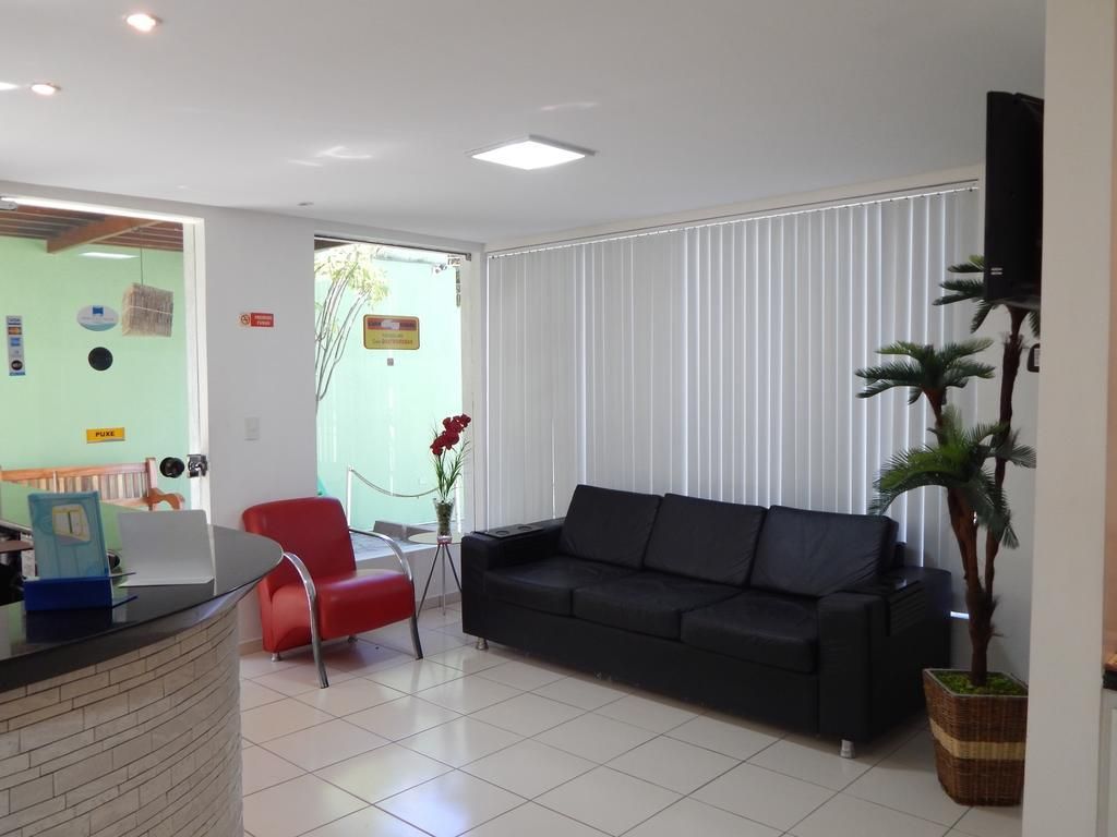 Uma sala de estar moderna com um sofá preto, uma poltrona vermelha e um balcão de recepção.