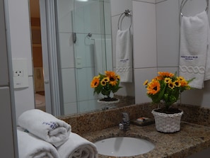 Een badkamer met een granieten aanrechtblad, een witte wastafel en twee potten met zonnebloemen.