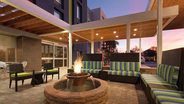 An outdoor patio with a fire pit, seating, and a covered area. - Home2 Suites by Hilton Orlando/International Drive South (Orlando)