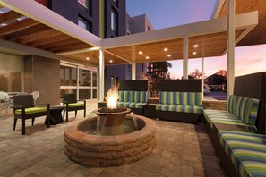 An outdoor patio with a fire pit, seating, and a covered area. - Home2 Suites by Hilton Orlando/International Drive South (Orlando)