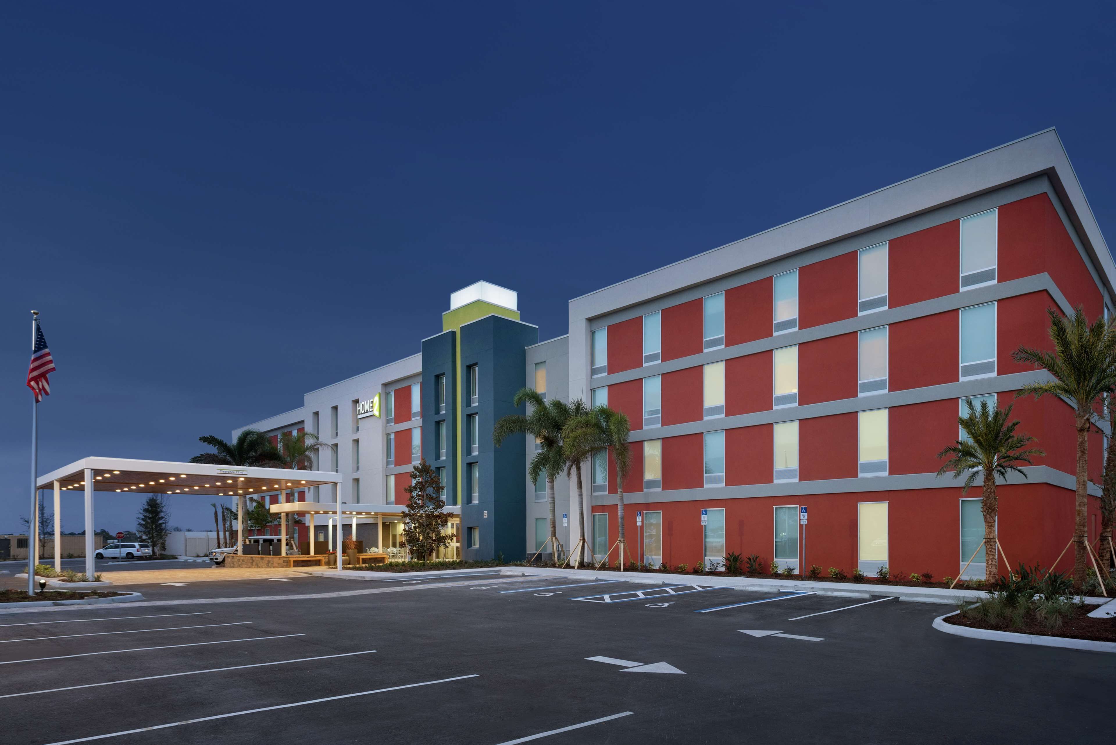 Un hôtel moderne avec une façade rouge, une entrée couverte et un parking.