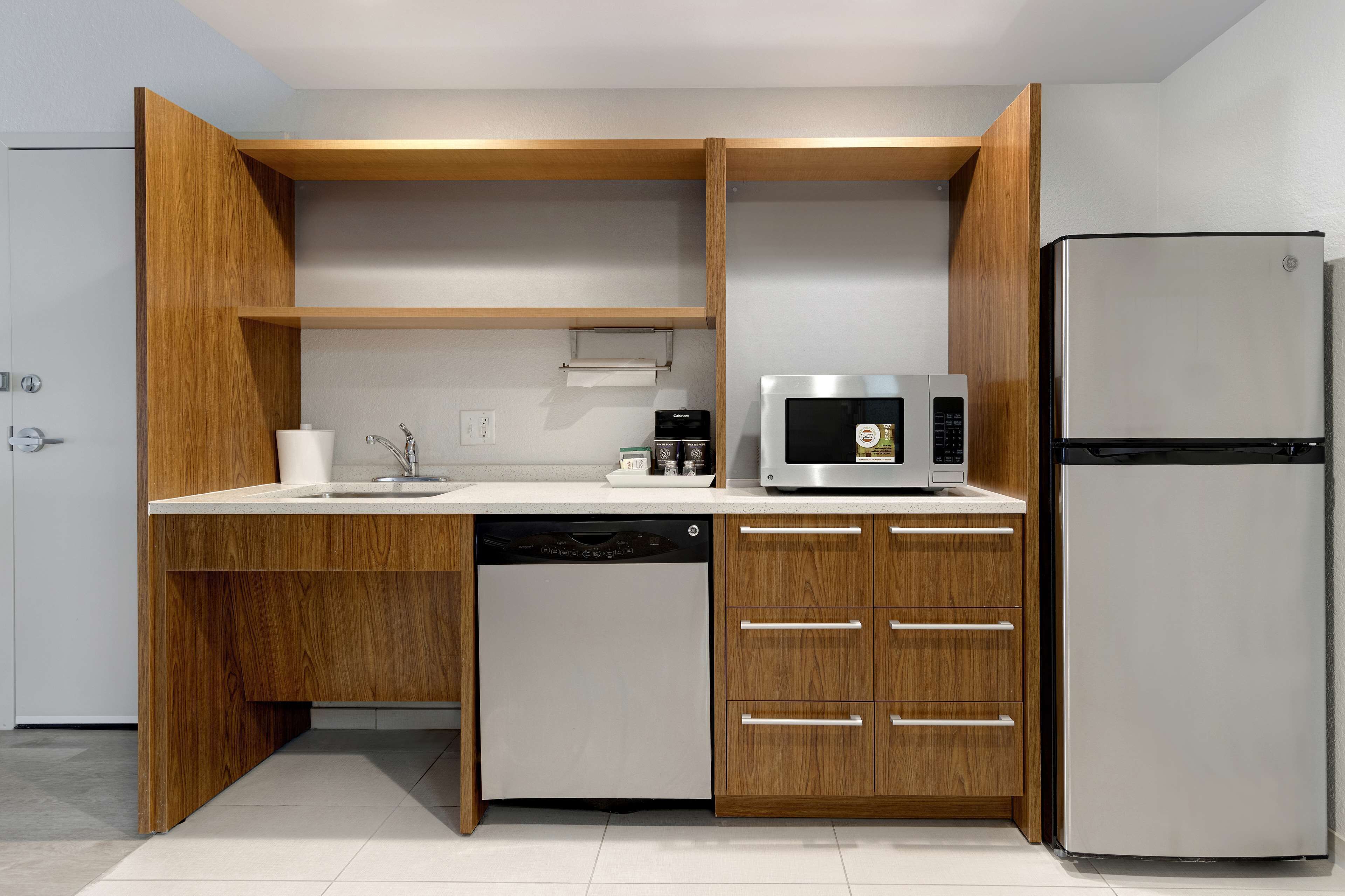 Une cuisine moderne dotée de meubles en bois, d’un lave-vaisselle, d’un four à micro-ondes et d’un réfrigérateur.