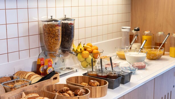 A breakfast buffet with various food items and condiments. - ibis budget Rennes Cesson (Cesson-Sevigne)
