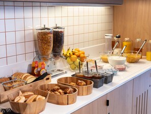 A breakfast buffet with various food items and condiments. - ibis budget Rennes Cesson (Cesson-Sevigne)