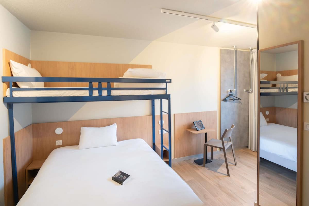 A bunk bed room with a desk, chair, and a mirror.