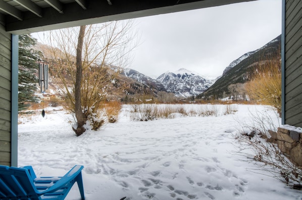 A covered outdoor area with a view of a snowy landscape and mountains.