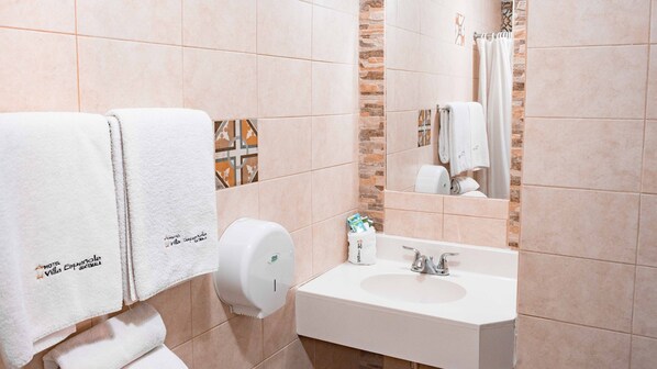 Baño con lavamanos, dispensador de toallas y espejo.