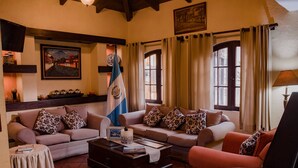 A cozy living room with two sofas, a coffee table, and a flag. - Hotel Villa Española (Guatemala City)