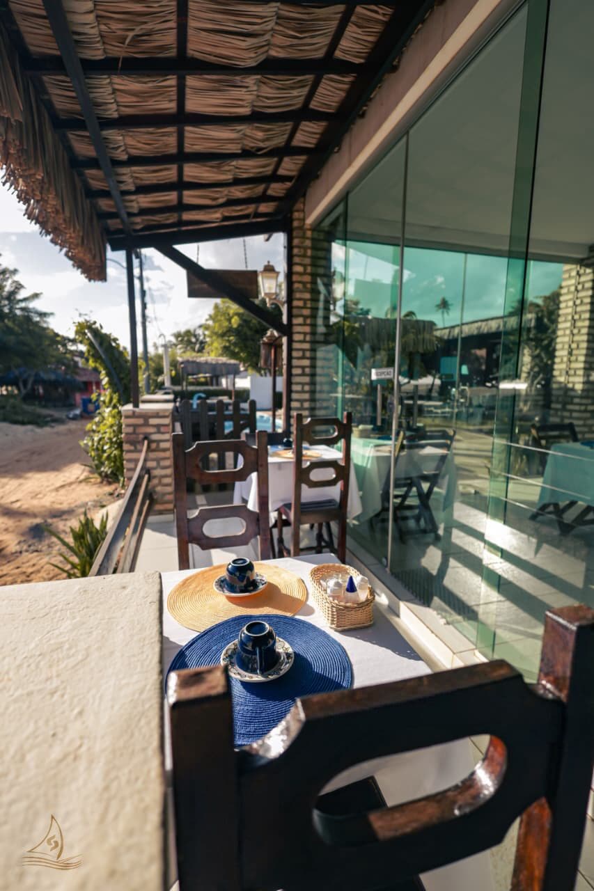 A covered outdoor seating area with tables, chairs, and a view of the surrounding landscape.