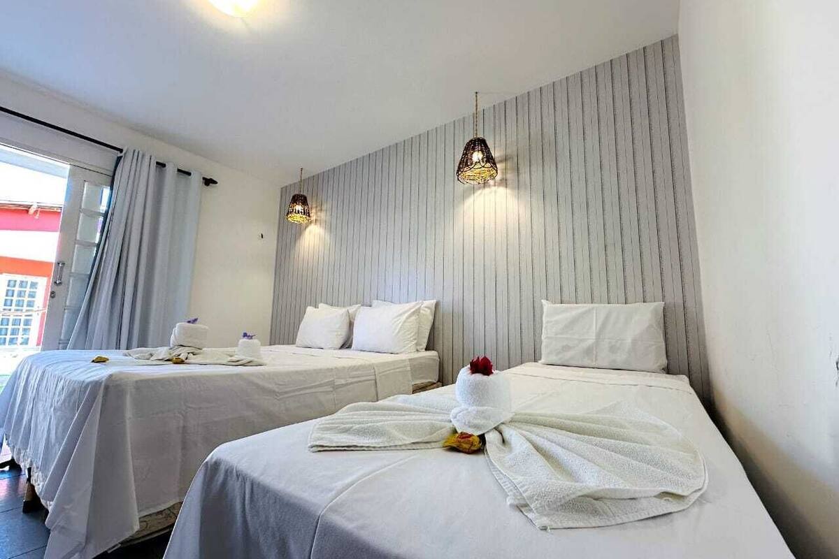 Une chambre d’hôtel avec deux lits, un mur à rayures et des lampes suspendues.