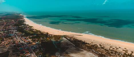 Vista aérea de un pueblo costero con playa, casas y una carretera.