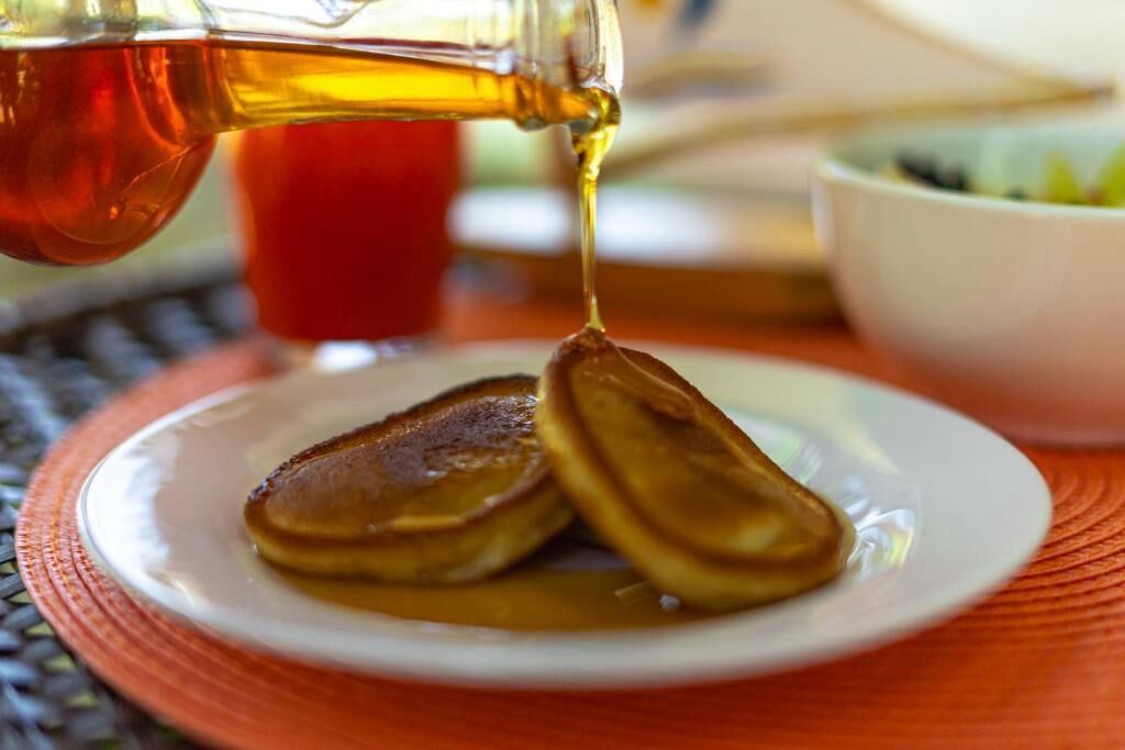 Pannkakor på en tallrik, med sirap som hälls över dem.