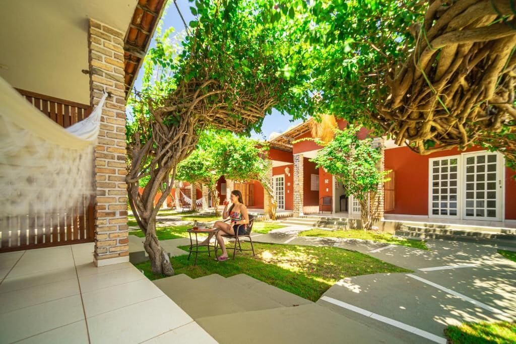 A courtyard with a covered seating area, a brick wall, and a tree with hanging roots.