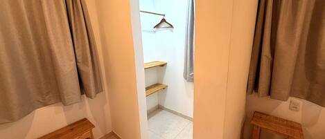 Ein schmaler Flur mit einer hölzernen Bank links, einem Holzregal in der Mitte und einem kleinen Holztisch rechts.