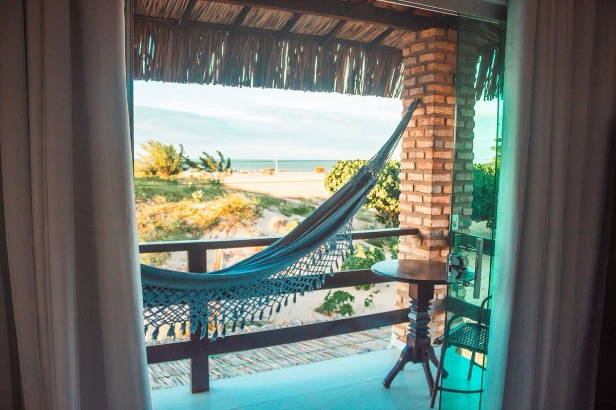 Un hamac sur un balcon avec vue sur la plage et l’océan.