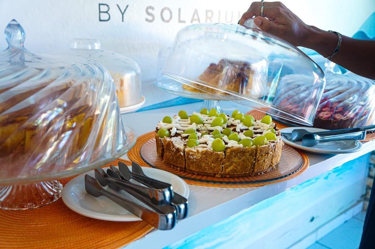 Un buffet con diversi cibi esposti sotto campane di vetro, tra cui una torta decorata con olive verdi.