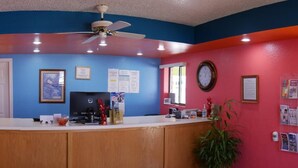A reception area with a counter, framed artwork, a clock, and a ceiling fan. - Morning Star Inn (Anson)