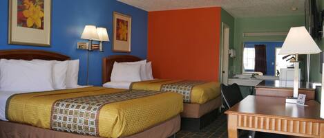 A hotel room with two beds, a desk, and a bathroom visible in the background.