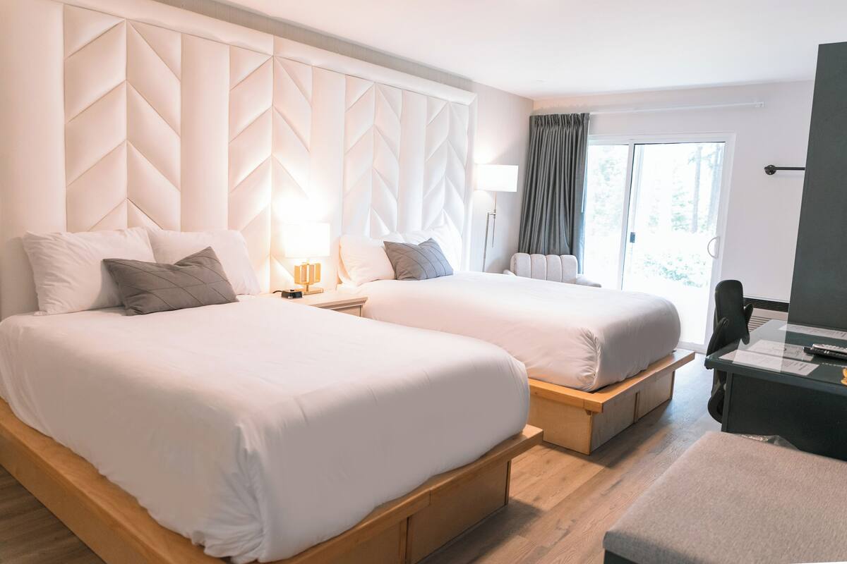 Ett hotellrum med två sängar, ett skrivbord och en stol.