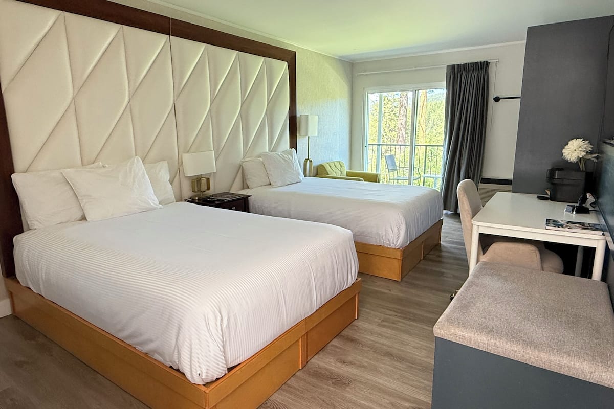 Ett hotellrum med två sängar, ett skrivbord och en stol.