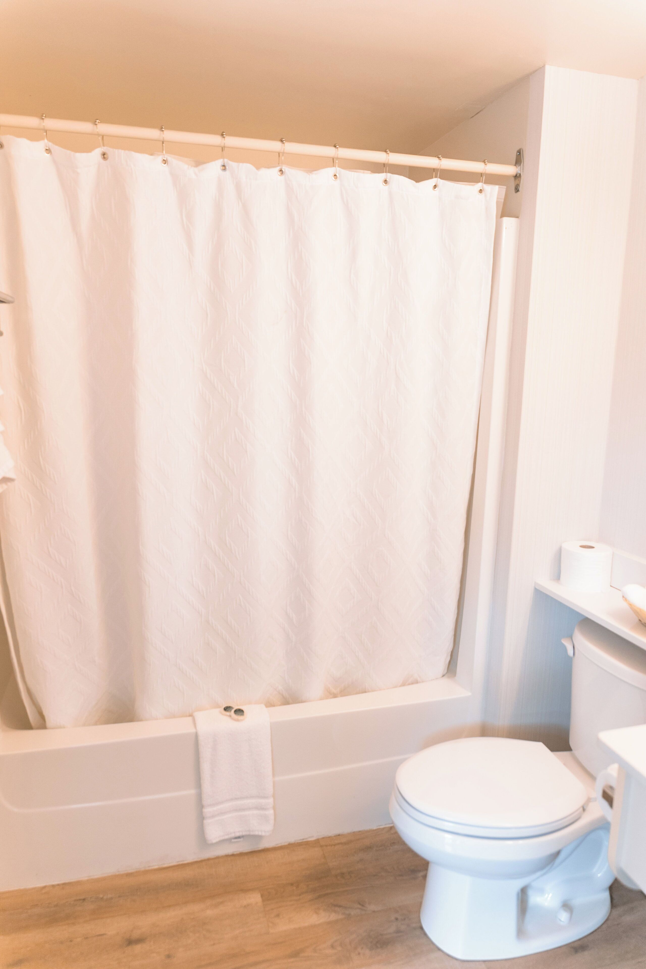 A bathroom with a bathtub, toilet, and a shower curtain.