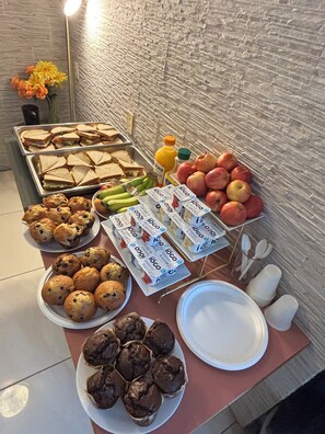 A buffet table with sandwiches, fruits, muffins, and juice cartons. - Hotel Civilia Lakeside by Civilia Golf Retreat (Clearwater)